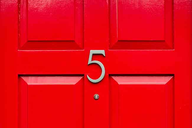 Bright red front door with the house number 5 and the five in elegant Silver metal with a peep hole den close up